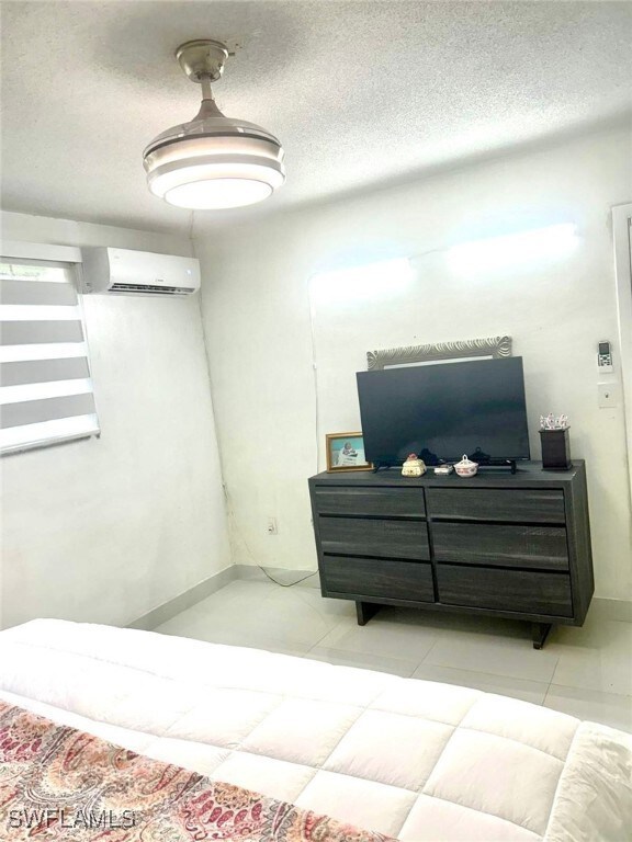 Bedroom featuring a wall unit AC, a textured ceili