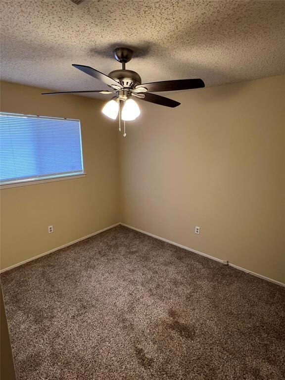 Spare room with a ceiling fan, carpet floors, a t