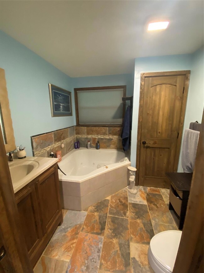 Bathroom featuring a relaxing tiled bath, toilet, 