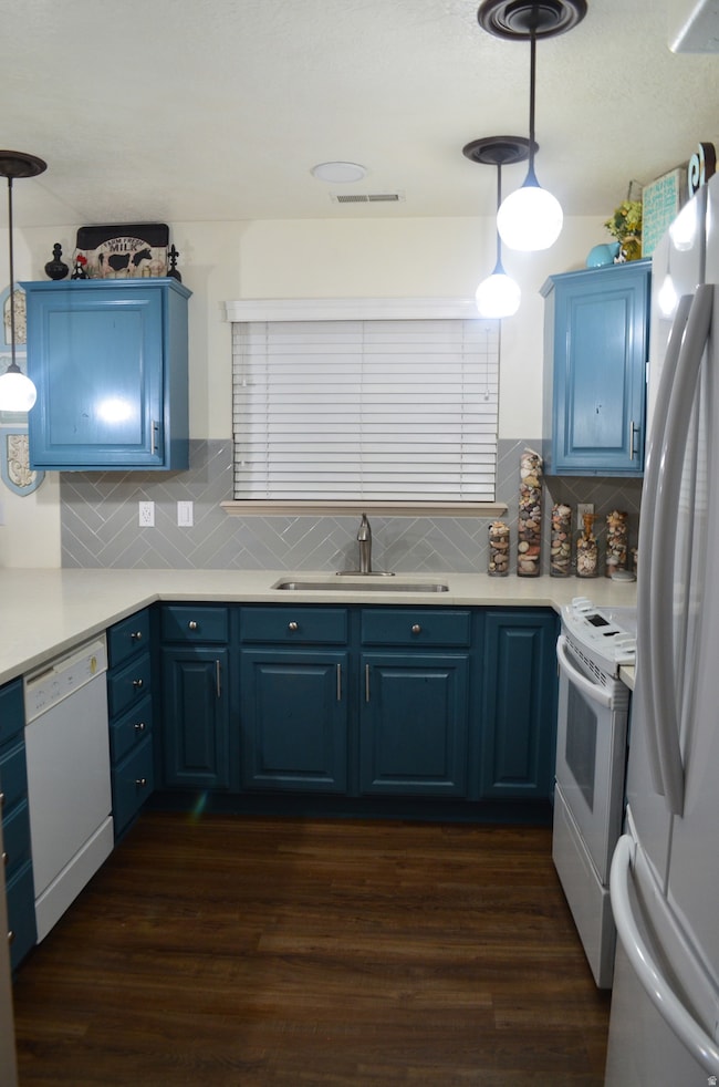Kitchen with hanging light fixtures, blue cabinets, and dark wood finished floors