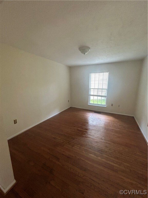 Empty room featuring a textured ceiling and dark h