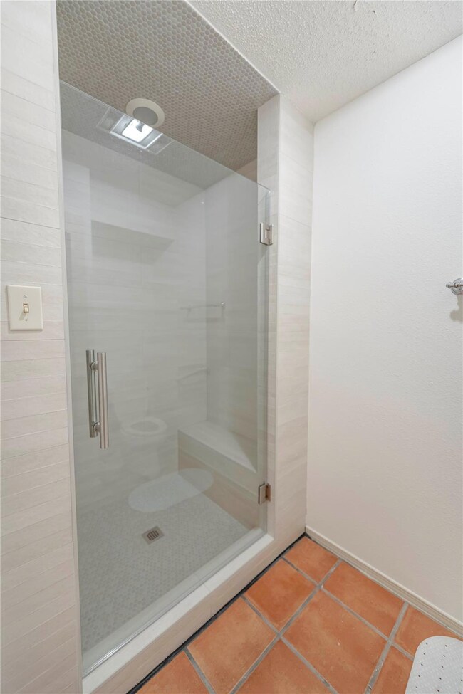 Bathroom with a shower stall and tile patterned f