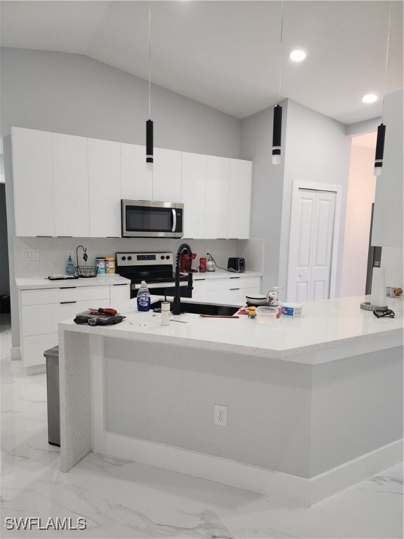 Kitchen featuring vaulted ceiling, white cabinets,