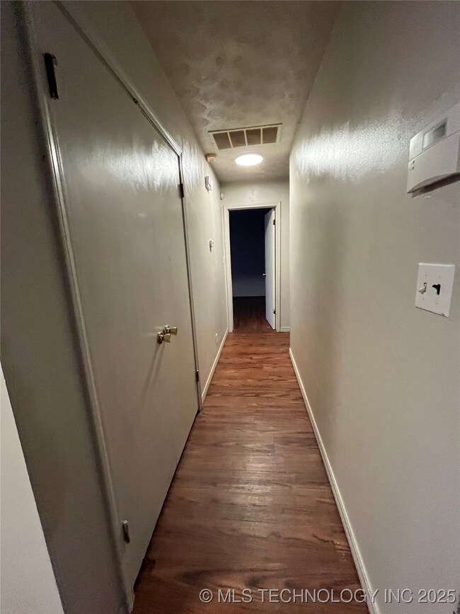Corridor featuring wood finished floors and basebo