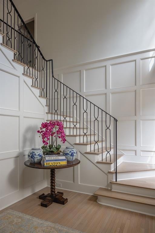 Staircase with wood finished floors and a decorati