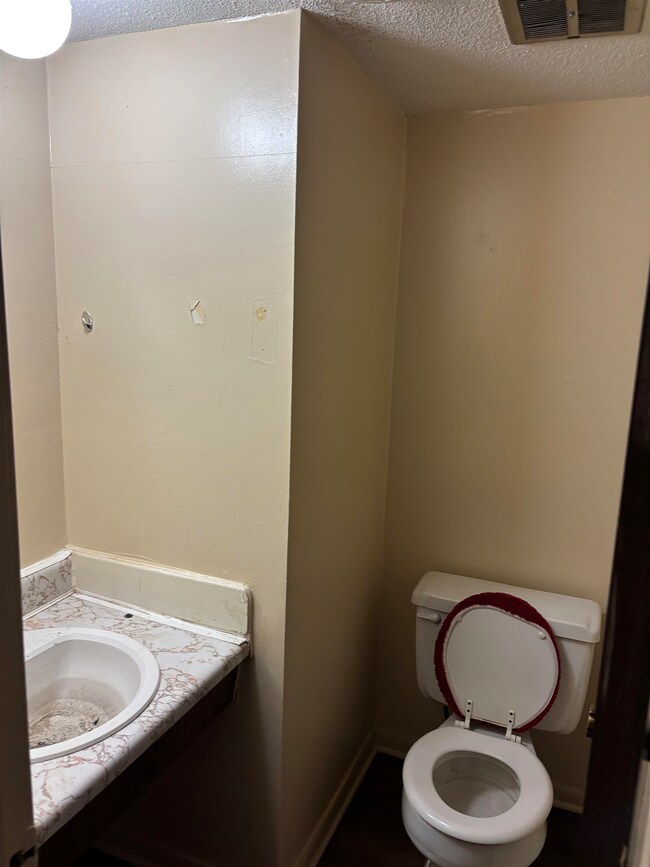 Bathroom featuring a textured ceiling, toilet, van