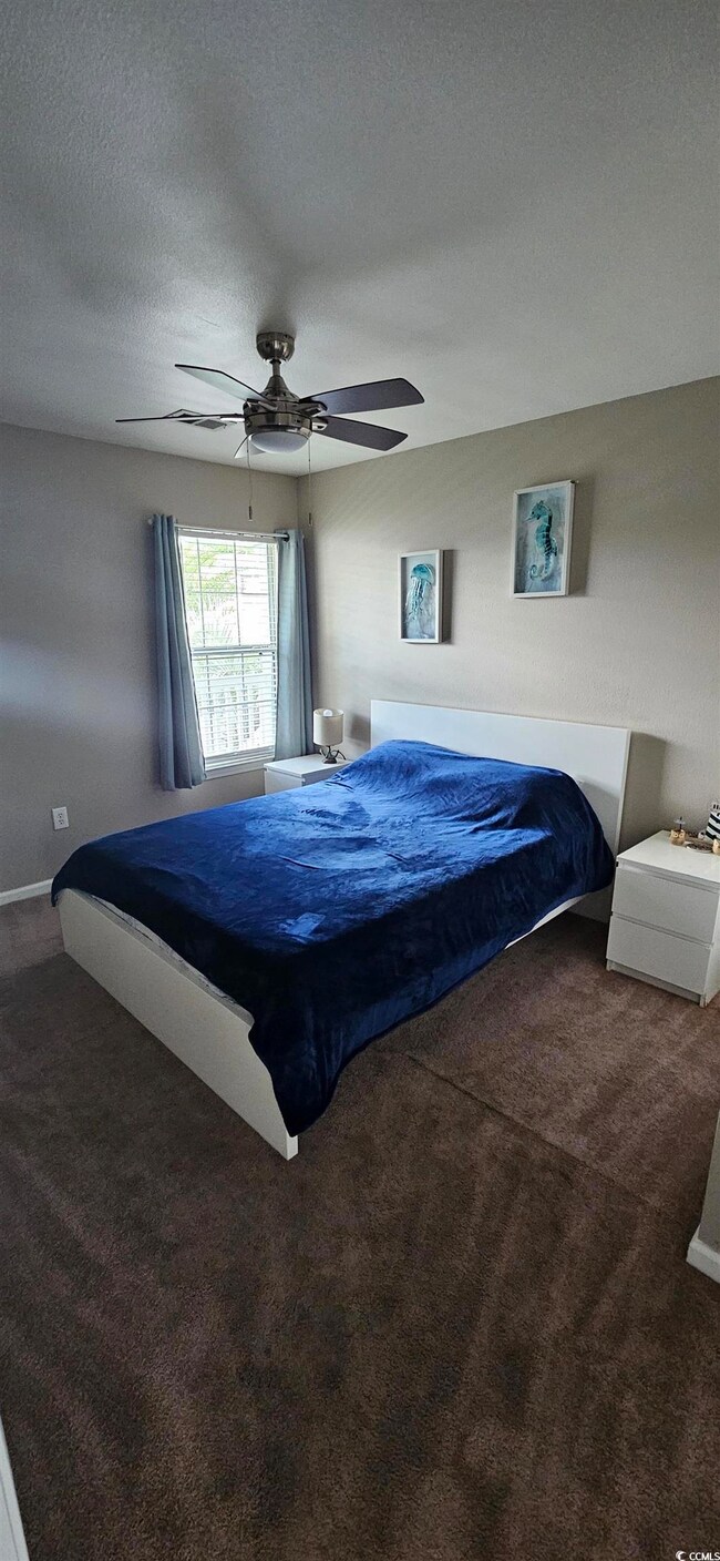 Carpeted bedroom with baseboards, ceiling fan, and