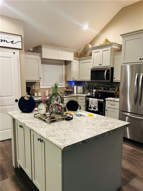 Kitchen featuring a center island, dark wood-style floors, appliances with stainless steel finishes, vaulted ceiling, and white cabinets