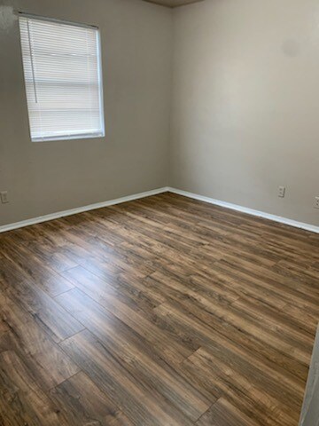 Spare room featuring dark wood-style flooring and baseboards
