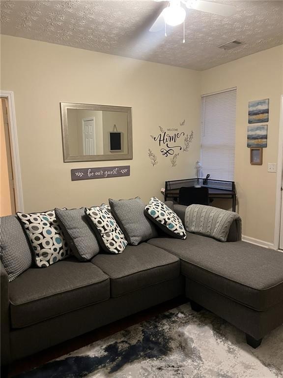 Living room with a textured ceiling and ceiling fan