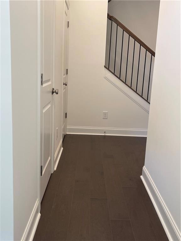 Corridor featuring baseboards and dark wood-type flooring