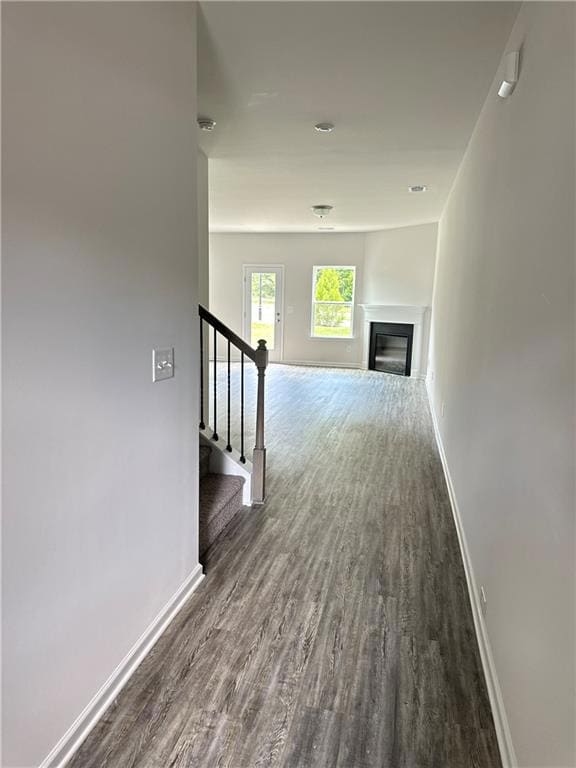 Corridor with wood finished floors, baseboards, an