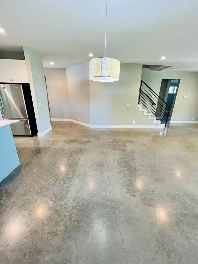 Unfurnished living room with concrete floors, sta
