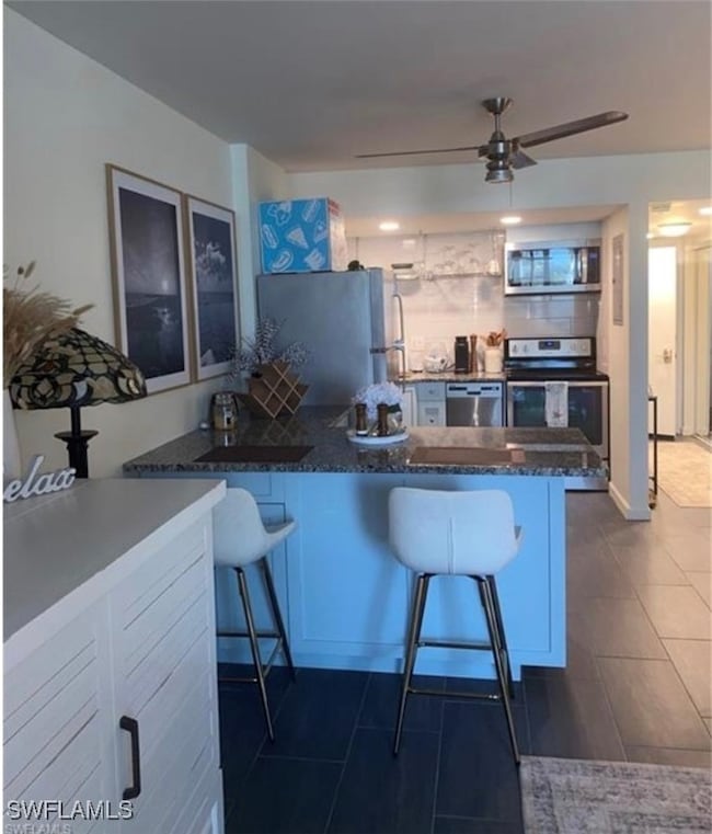 Kitchen with a breakfast bar, stainless steel appliances, a peninsula, and tasteful backsplash