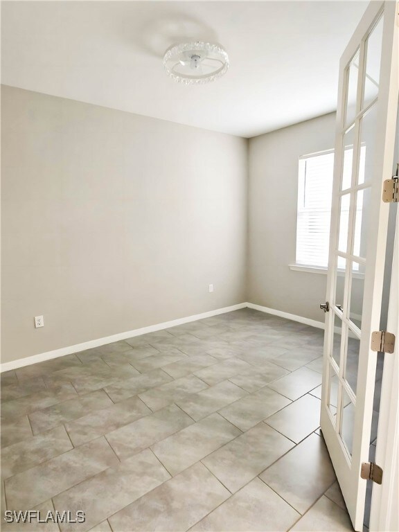 Empty room featuring baseboards, french doors, and