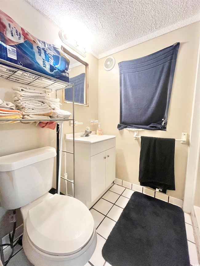 Half bathroom with tile patterned flooring, vanity, toilet, a textured ceiling, and baseboards
