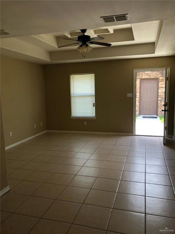 Tiled spare room with a raised ceiling, ceiling fan, and baseboards