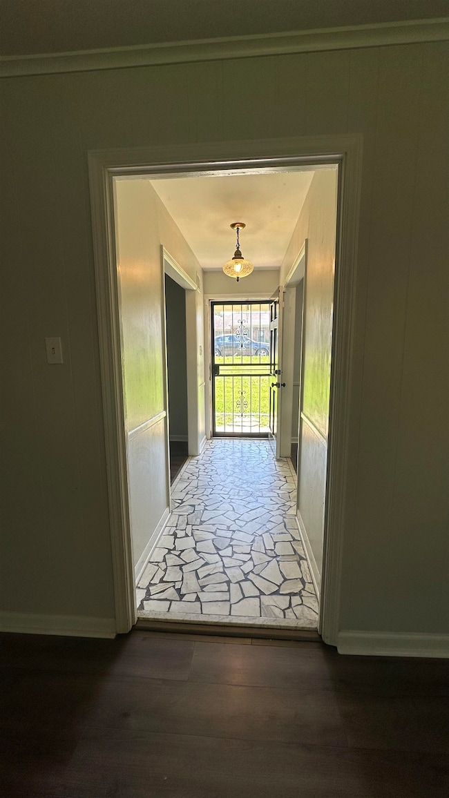 Corridor with wood finished floors and a decorative wall