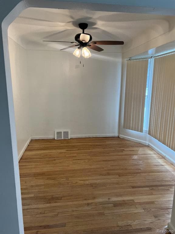 Unfurnished room featuring light wood finished floors, arched walkways, and a ceiling fan