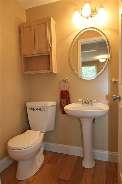 Powder room with wood flooring, pedestal sink...