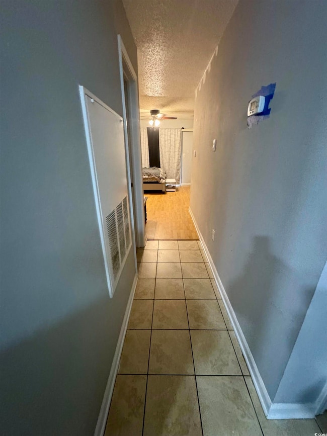 Hall with a textured ceiling and light tile patterned floors