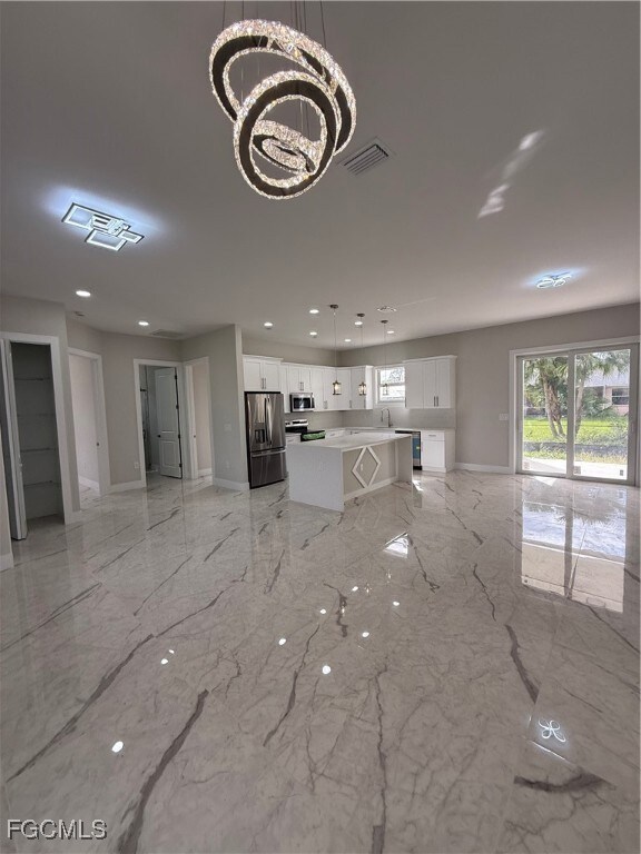 Unfurnished living room featuring light marble finish floors, a chandelier, and recessed lighting