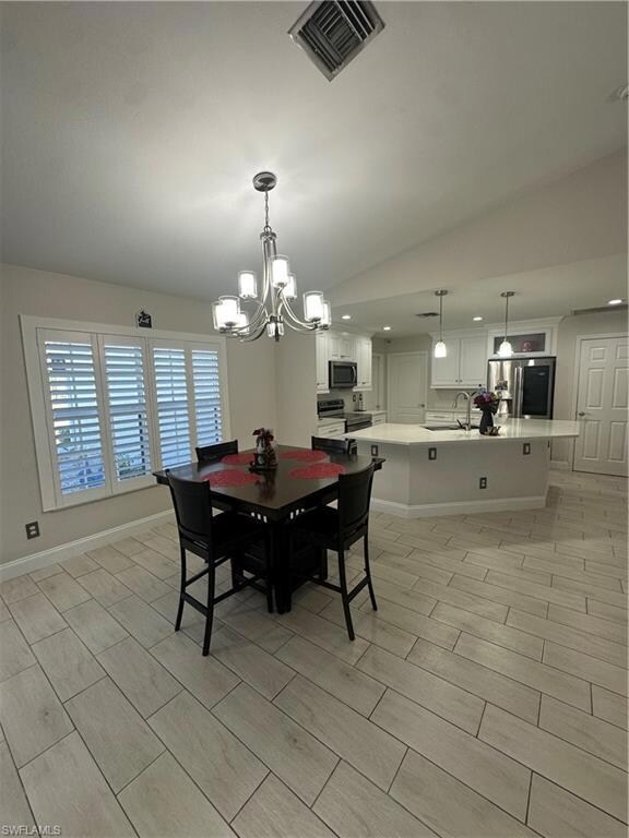 Dining area featuring lofted ceiling, sink, and a notable chandelier