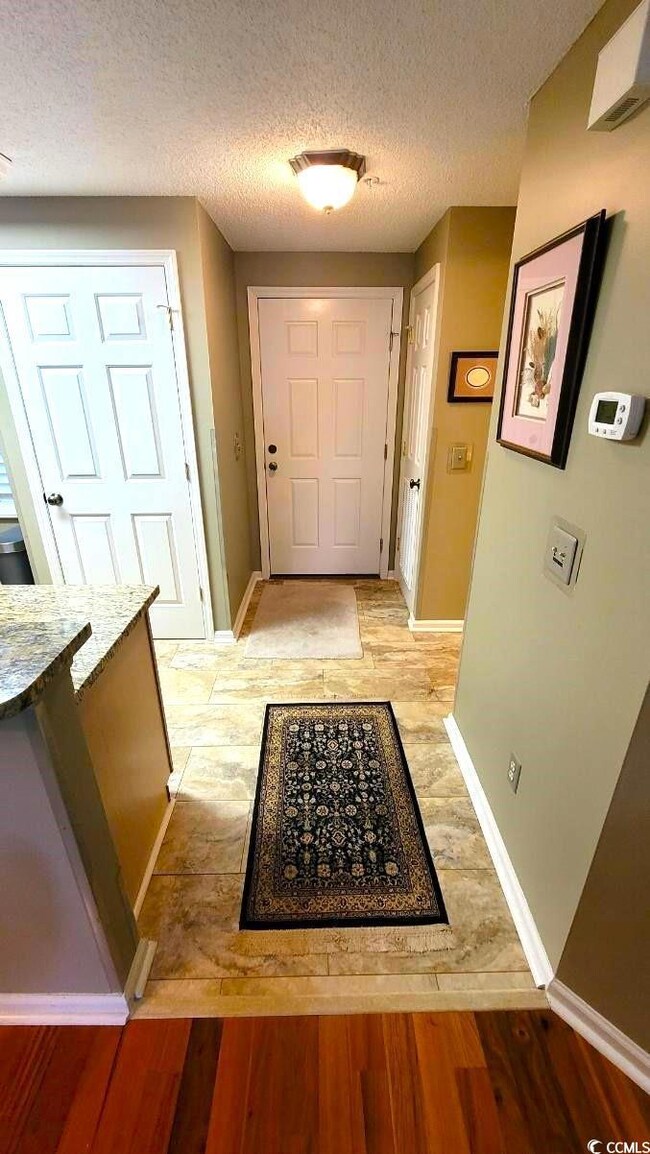 Hallway featuring a textured ceiling and light woo