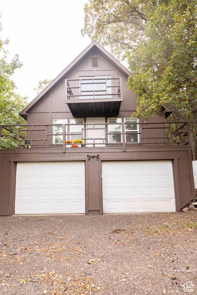 View of front facade with a balcony, driveway, and a garage