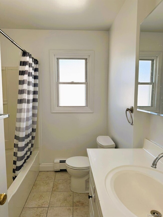 Bathroom featuring vanity, light tile patterned floors, plenty of natural light, and shower / tub combo