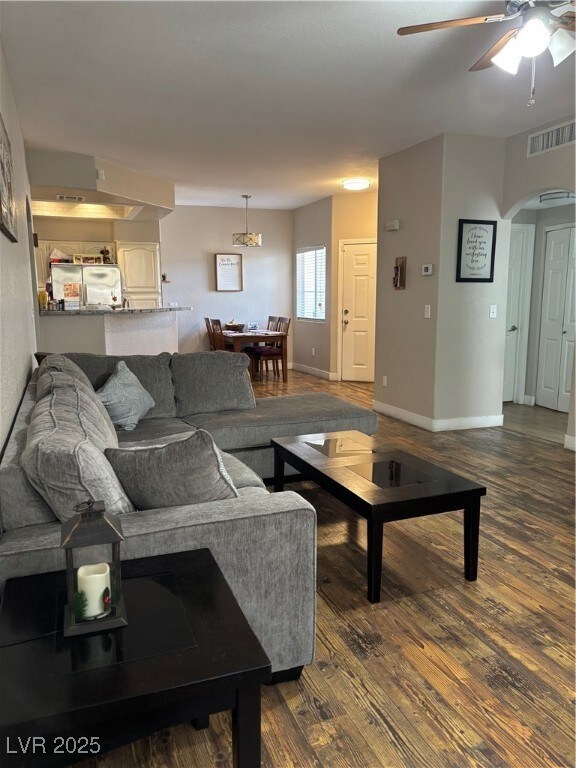 Living room with arched walkways, dark wood finish