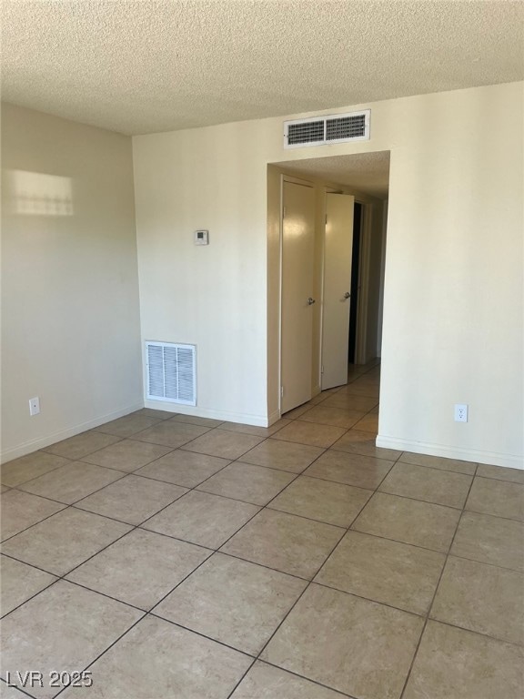 Unfurnished room featuring a textured ceiling, lig
