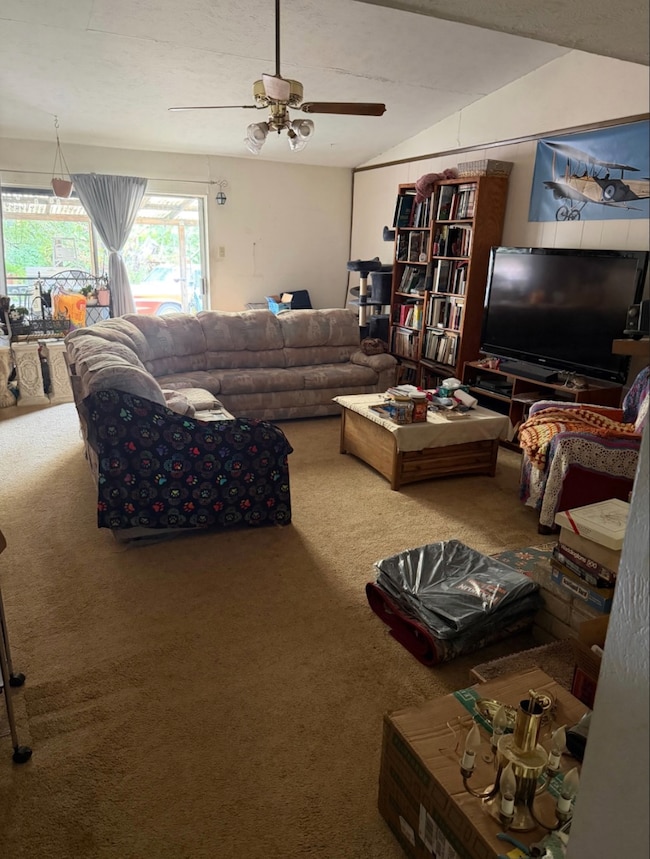 Living room with carpet, a ceiling fan, and vaulted ceiling