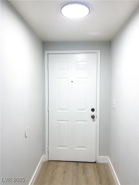 Entryway with baseboards and light wood-type floor