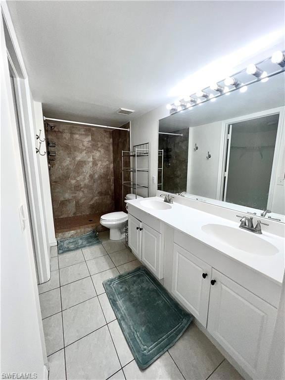 Bathroom featuring tiled shower, double vanity, and tile patterned flooring