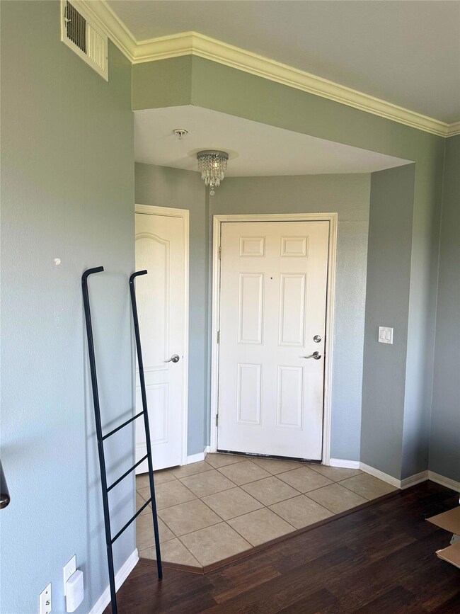 Foyer with wood finished floors, baseboards, crow