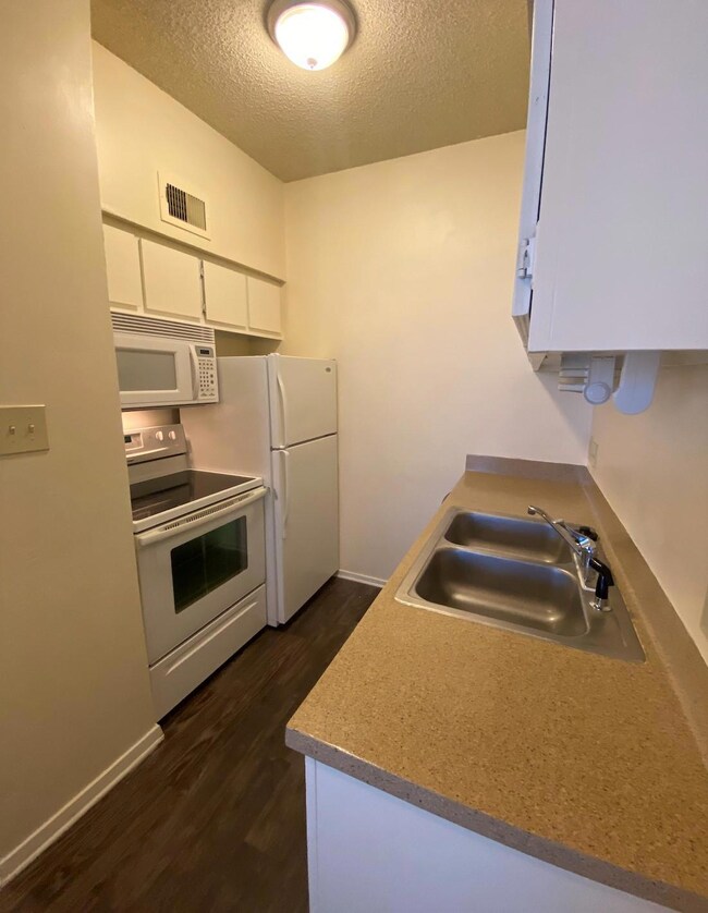 Kitchen featuring a textured ceiling, dark wood-s