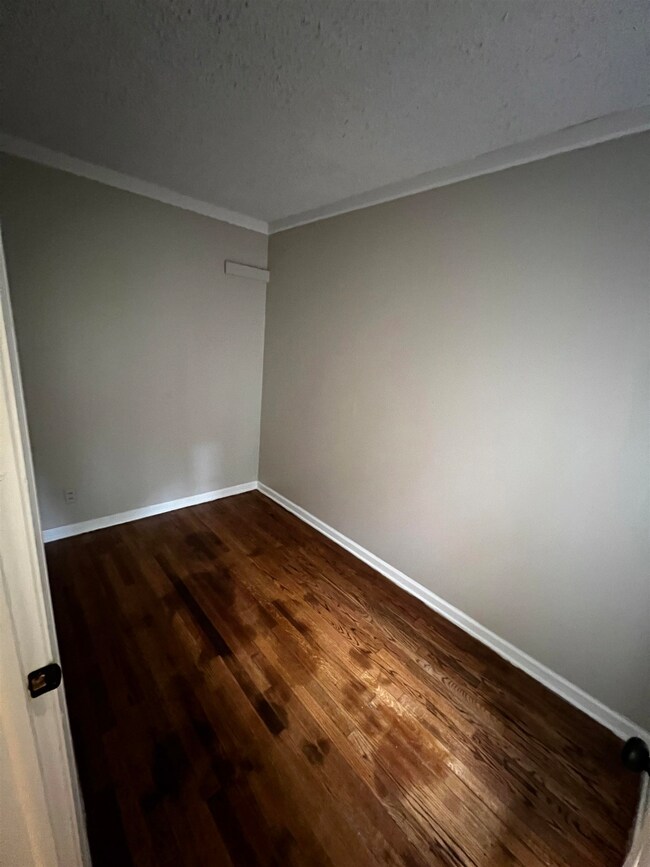 Unfurnished room with crown molding, dark wood-sty