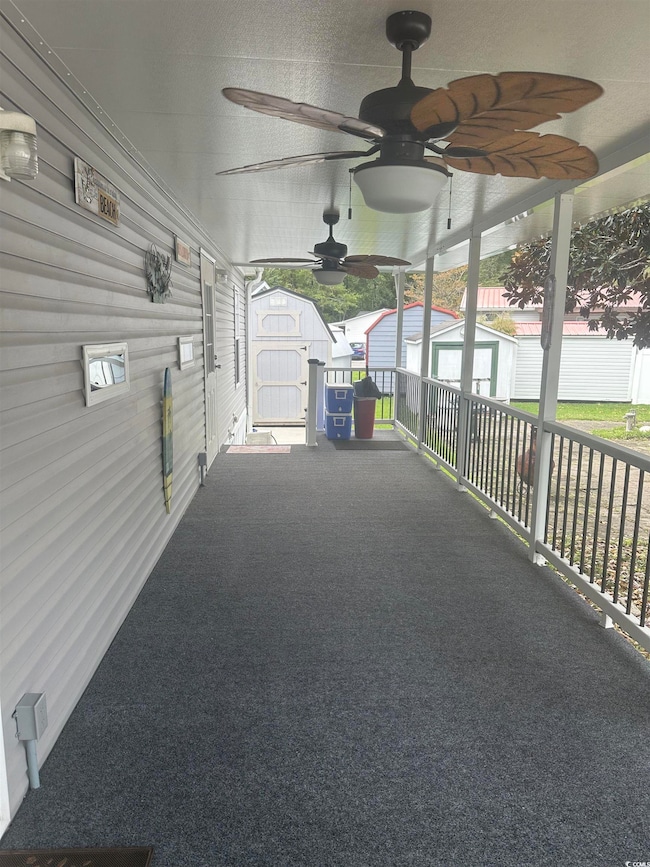 View of patio featuring a shed, a ceiling fan, and a sunroom