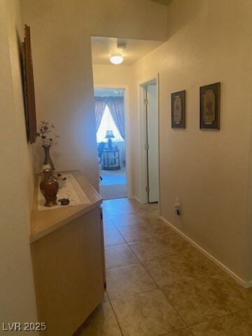 Hallway with light tile patterned floors and baseb