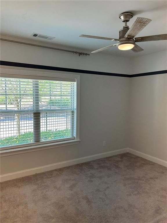 Carpeted empty room with visible vents, baseboards