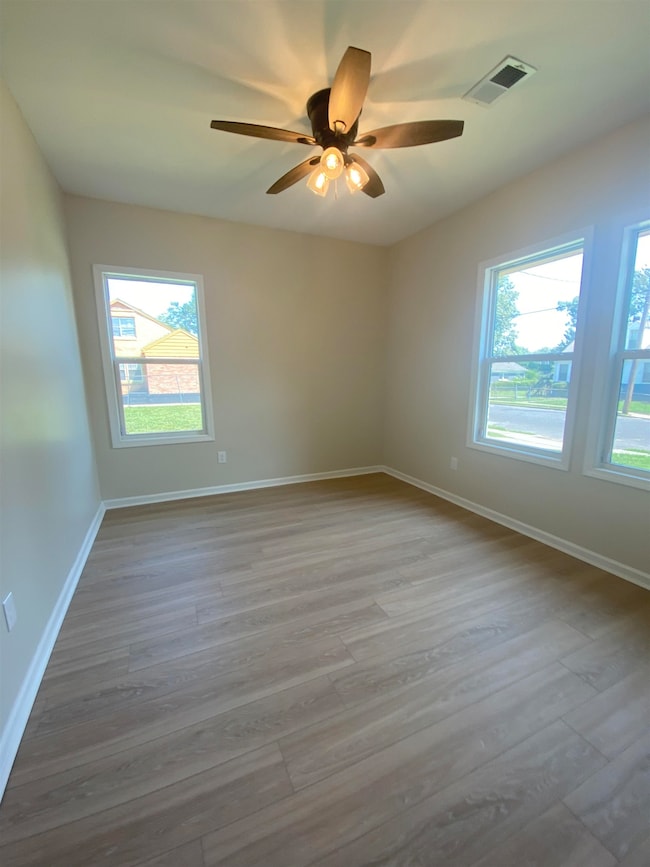 Empty room featuring plenty of natural light, light wood-type flooring, and ceiling fan