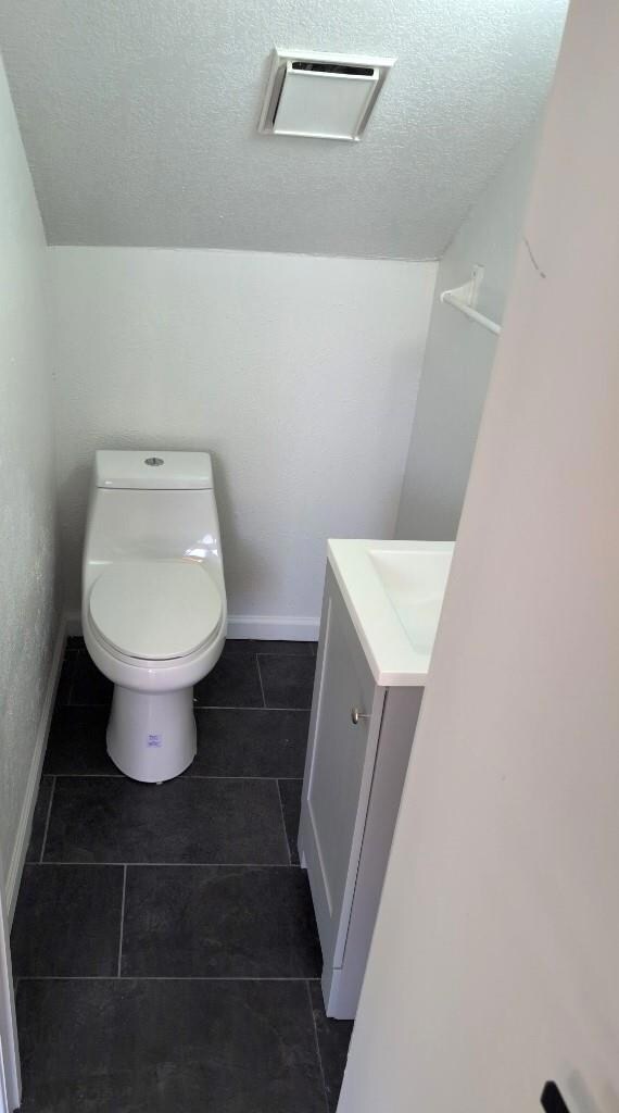 Bathroom featuring baseboards, toilet, vanity, an