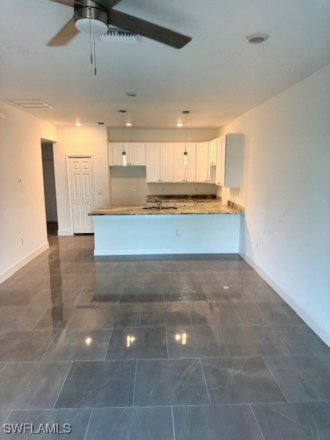 Kitchen with baseboards, white cabinetry, a penins