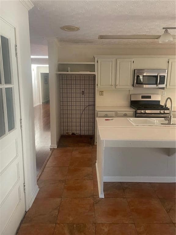 Kitchen featuring a textured ceiling, dark tile pa