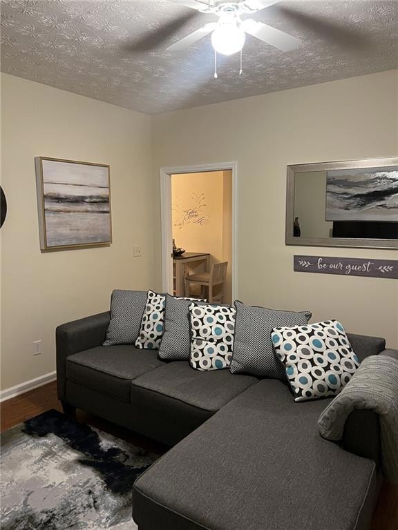 Living area featuring wood finished floors, ceiling fan, and a textured ceiling