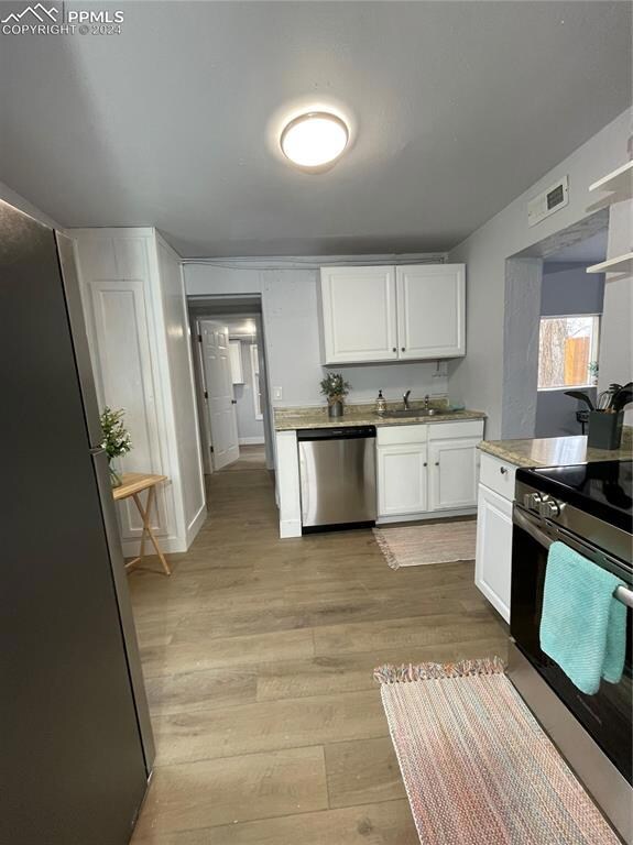 Kitchen featuring stove, dishwasher, white cabinet