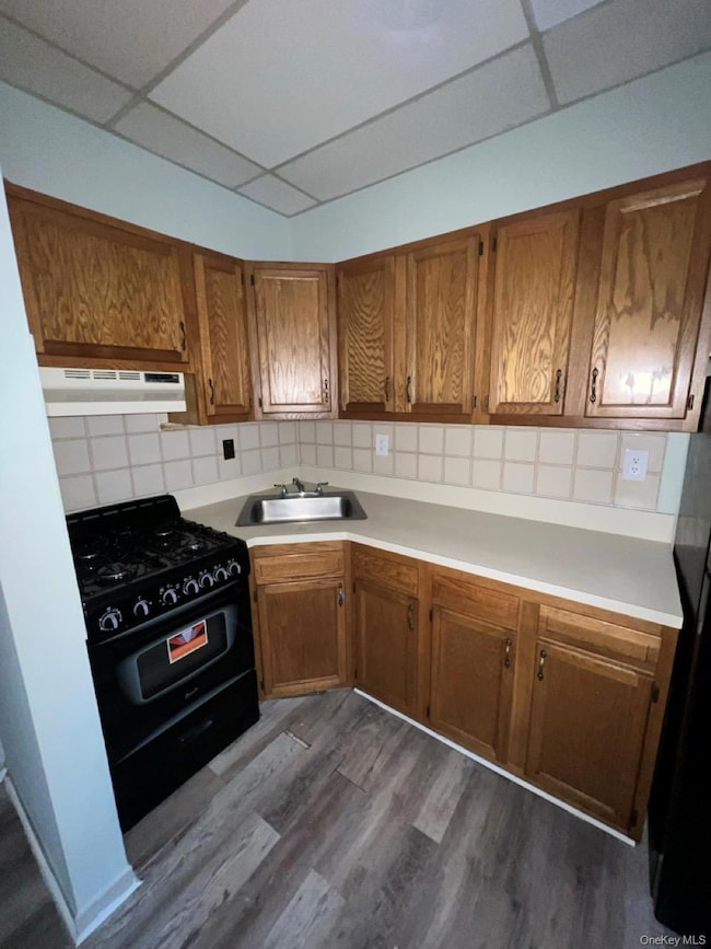 Kitchen with brown cabinets, a drop ceiling, gas stove, and light countertops
