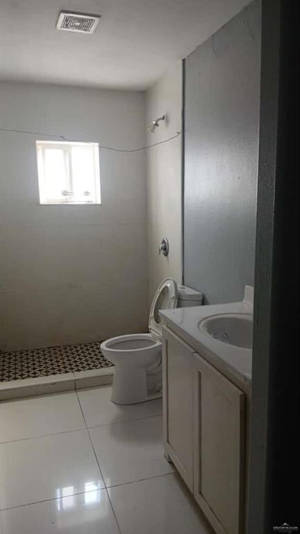 Bathroom with vanity, light tile patterned flooring, and tiled shower