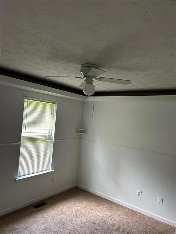 Unfurnished room with light carpet, a textured ceiling, and a ceiling fan
